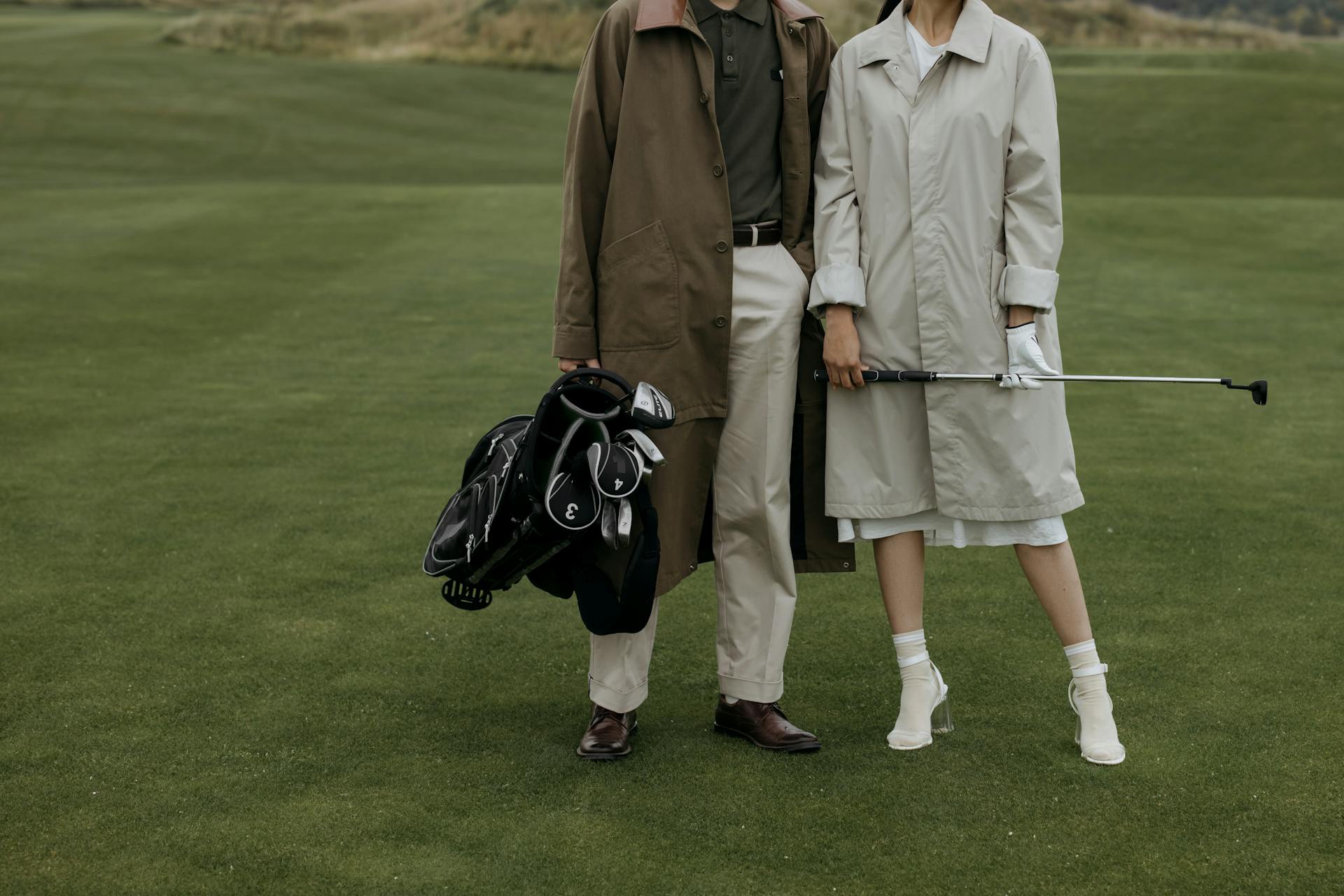 a couple dress in fancy clothes hold golf clubs